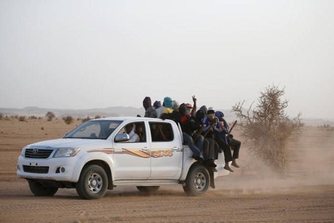 Migrants crossing the Sahara desert into Libya ride on the back of a pickup truck outside Agadez, Niger, May 9, 2016. REUTERS/Joe Penney
