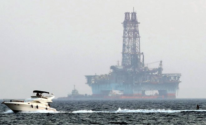An offshore drilling rig is seen as a boat passes with a skier, in the waters of the Eastern Mediterranean, July 5, 2020. (AP Photo)