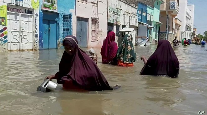 People wade through a flooded street in Beledweyne, central Somalia, in this image made from video, May 17, 2020.