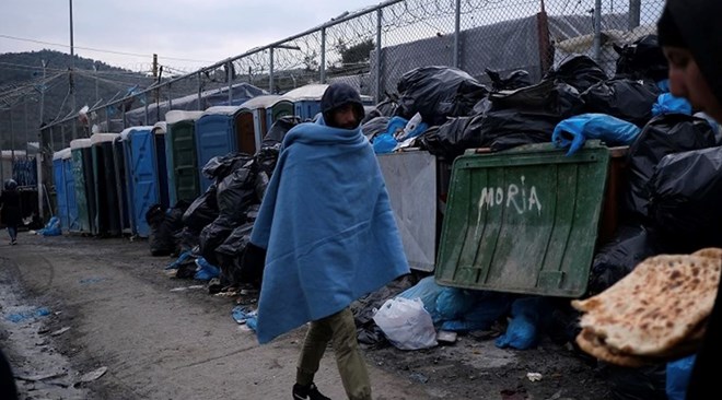 A migrant covered with a blanket passes in front of dumped garbage outside the Moria refugee camp on the northeastern Aegean island of Lesbos, Greece Source: AAP Image/AP Photo/Aggelos Barai