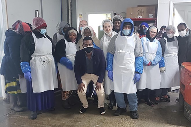 Workers pose with mediator Cadi Adan (center) and Salad Makers Inc. owner Tom Jacobson (back row, center) at the end of their successful negotiation. Credit: Photo courtesy of Cani Adan