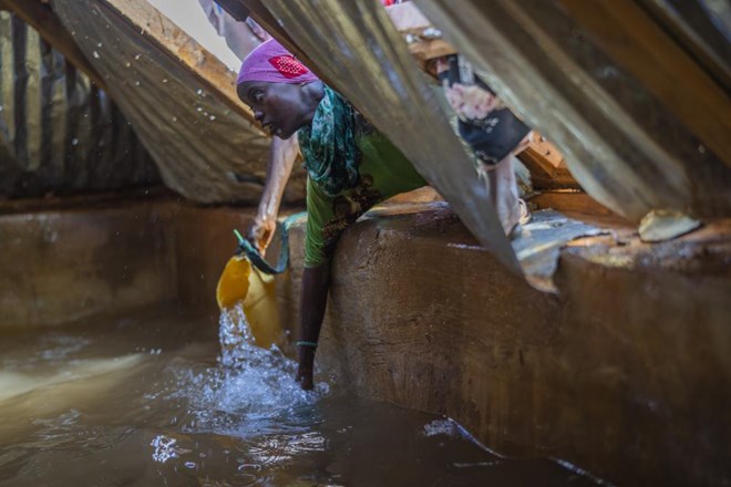 A Somali woman fills a container with water at a camp for displaced people on the outskirts of Dollow, Somalia on Tuesday, Sept. 20, 2022. Somalia has long known droughts, but the climate shocks are now coming more frequently, leaving less room to recover and prepare for the next. (AP Photo/Jerome Delay)