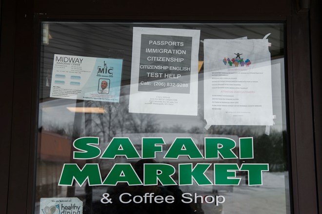 Signs on the door of Safari Market, a Somali-owned coffee shop and grocer that caters to the local Muslim community, advertise services for immigrants. (Andrew Cullen/For The Washington Post)
