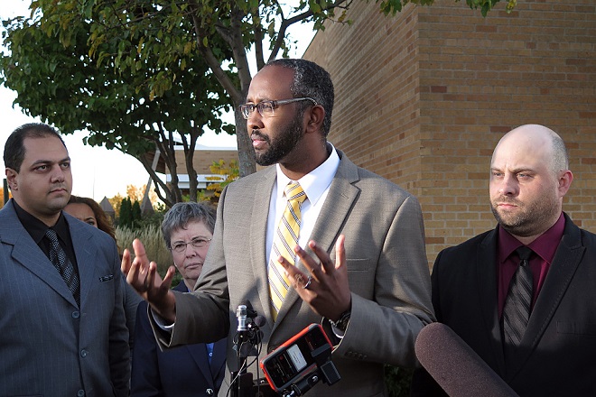 Jaylani Hussein, center, talked to reporters who were covering the resignation of Grant Nichols, right, outside Columbia Heights High School in Columbia Heights, Minn., on Tuesday, Oct. 13, 2015. A comment on Nichols' Facebook account sparked a student walk-out in September and ultimately Nichols' resignation from the Columbia Heights school board. Mukhtar Ibrahim | MPR News