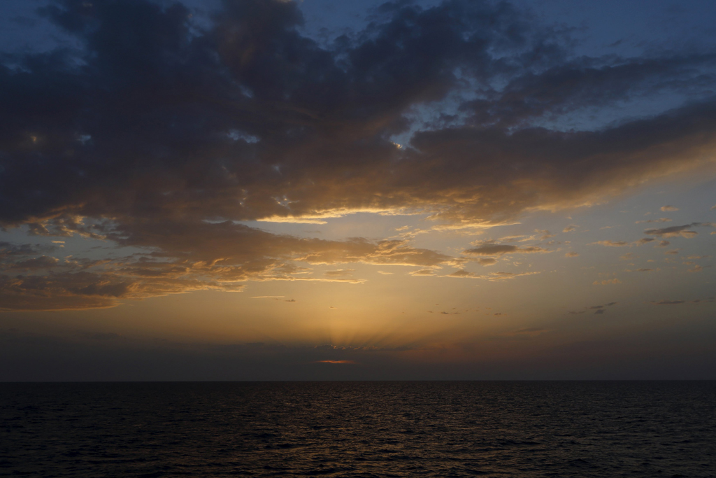 The sun sets over the area where a search for missing migrants is taking place after their boat capsized off the coast of Libya August 5, 2015.