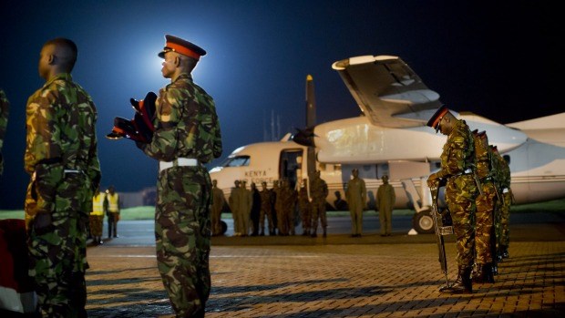 An honor guard, right, bows their heads while a soldier, as they stand by the coffins of four Kenyan soldiers killed in Somalia last week. Photo: Ben Curtis