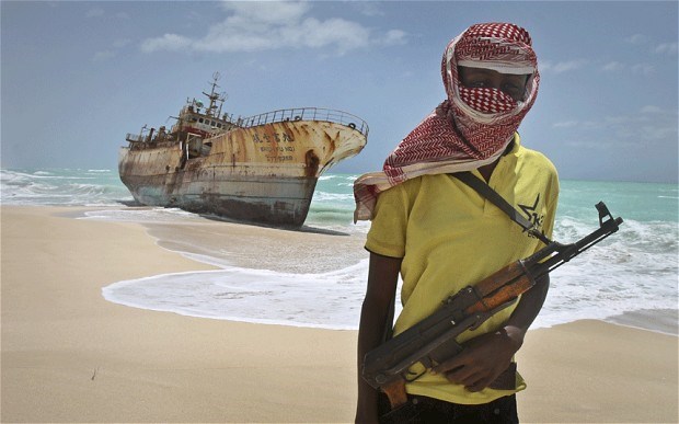 Scourge of the seas: a masked Somali pirate stands near a hijacked Taiwanese fishing vessel n the once-bustling pirate den of Hobyo, Somalia. Photo: AP Photo/Farah Abdi Warsameh