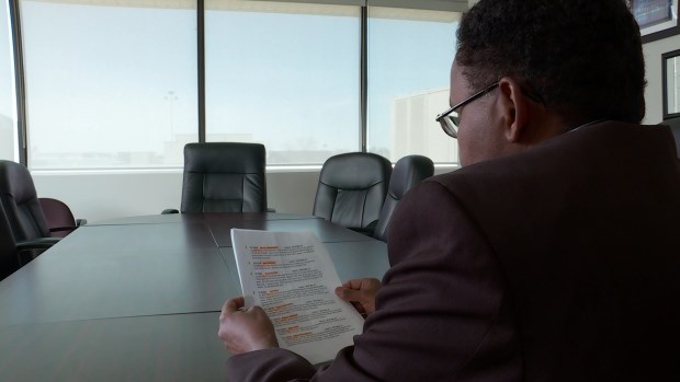 Jibril Ibrahim, the president of Edmonton's Somali-Canadian Cultural Society, reviews the list of renewed rewards. (CBC)