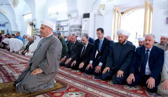 Syria’s President Bashar al-Assad (3rd R) attends prayers on the first day of Eid al-Fitr, inside a mosque in Hama (SANA Handout via Reuters)