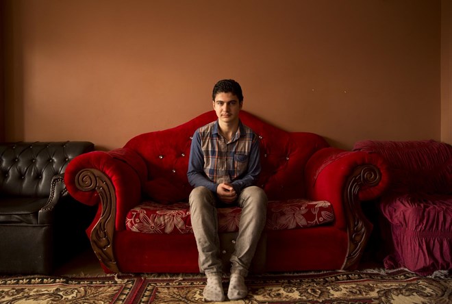 Syrian teenager Hasib Rifat Moustafa poses for a photo in the apartment he shares with his sister's family in the Middle East on Tuesday, Feb. 27, 2018. In July 2016, Alizabet Yandem and four of her children joined her husband, Rifat Moustafa, a lawyer who said he fled his native Syria after he was jailed and beaten with an electric cable for criticizing the Assad regime's record on human rights. But their son, Hasib, remained in the Middle East after officials held up his petition. Moustafa suspected an objection to his son's malformed left arm and hand, which need surgery. But the family expected approval within months. Then the new administration took office, and the case stalled. (AP Photo/maya Alleruzzo)