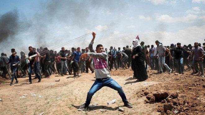 A Palestinian demonstrator throws a stone during a protest against the US Embassy move to Jerusalem and ahead of the 70th anniversary of Nakba, at the Gaza-Israeli border, in Abu Safia, Gaza Strip, May 14, 2018.
