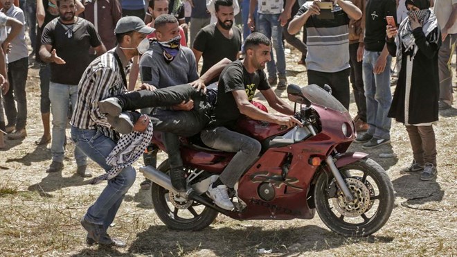 Mahmud Hams / AFP/Getty Images
Palestinians carry an injured man on a motorcycle during clashes with Israeli forces near the border between the Gaza strip and Israel east of Gaza City on May 14, 2018, as Palestinians protest over the inauguration of the US embassy following its controversial move to Jerusalem.