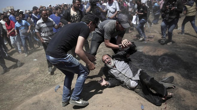 An elderly Palestinian man falls on the ground after being shot by Israeli troops during a deadly protest at the Gaza Strip's border with Israel, east of Khan Younis, Gaza Strip, Monday, May 14, 2018 - Khalil Hamra / AP