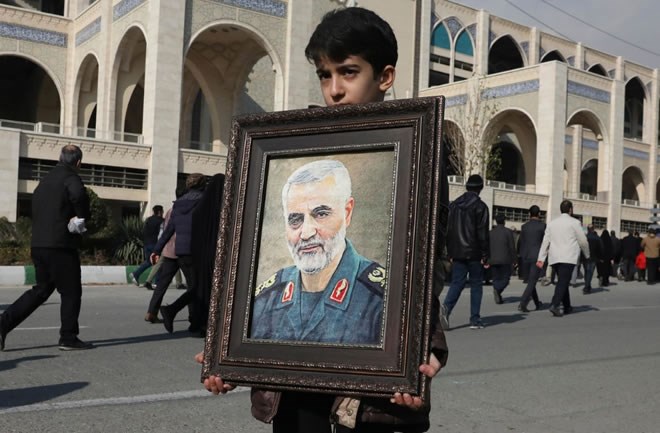 A boy carries a portrait of Iranian Revolutionary Guard Gen. Qassem Soleimani, who was killed in the U.S. airstrike in Iraq, prior to the Friday prayers in Tehran, Iran, Friday Jan. 3, 2020. Iran has vowed "harsh retaliation" for the U.S. airstrike near Baghdad's airport that killed Tehran's top general and the architect of its interventions across the Middle East, as tensions soared in the wake of the targeted killing. (AP Photo/Vahid Salemi)